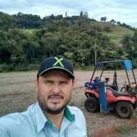 Selfie de um homem com um quadriciclo agrícola de fundo no campo